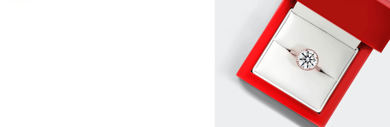 A diamond engagement ring with a round diamond cut set in a red jewelry box.