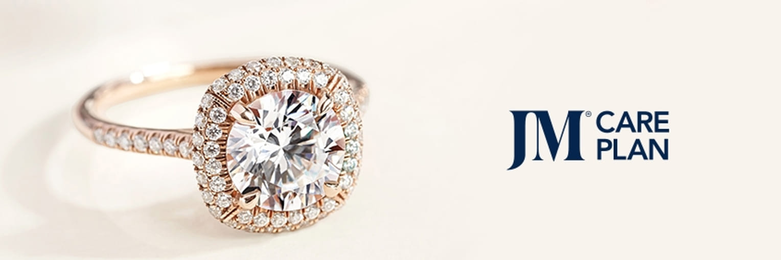 Elegant diamond ring with intricate setting on a light background, accompanied by 'JM Care Plan' text."