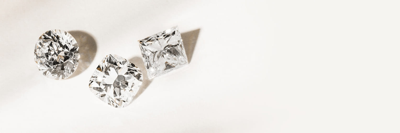 Three sparkling gemstones in different cuts displayed on a light background."