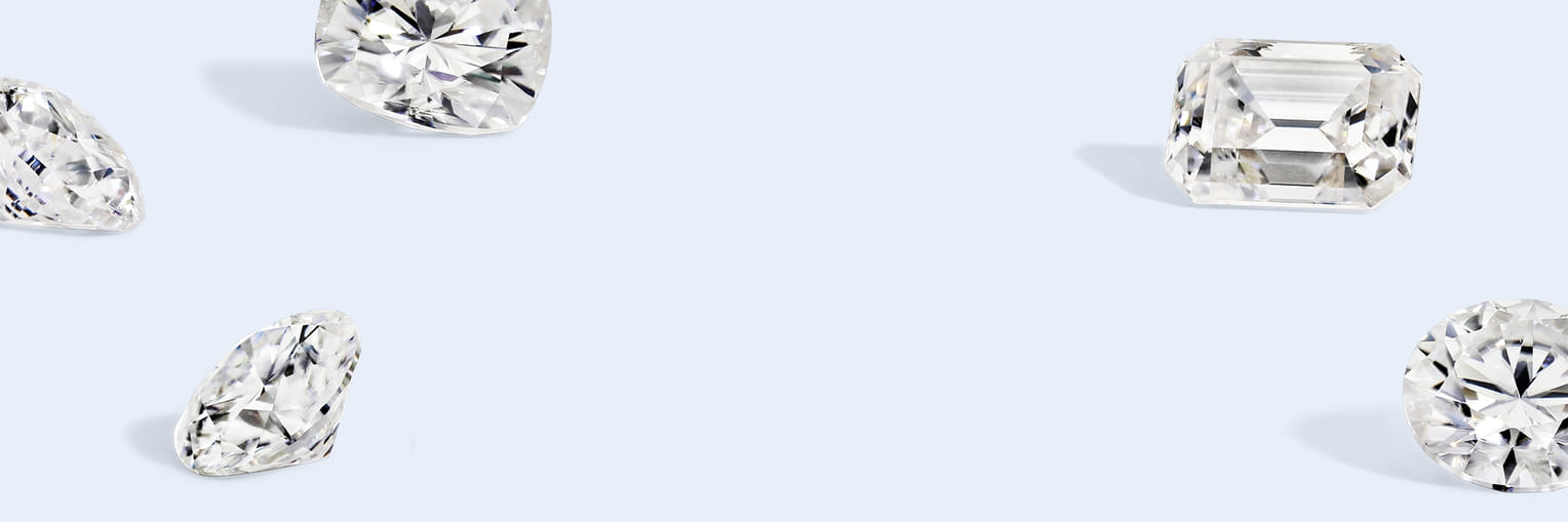 Various cut diamonds scattered on a light blue background, showcasing different shapes and facets."